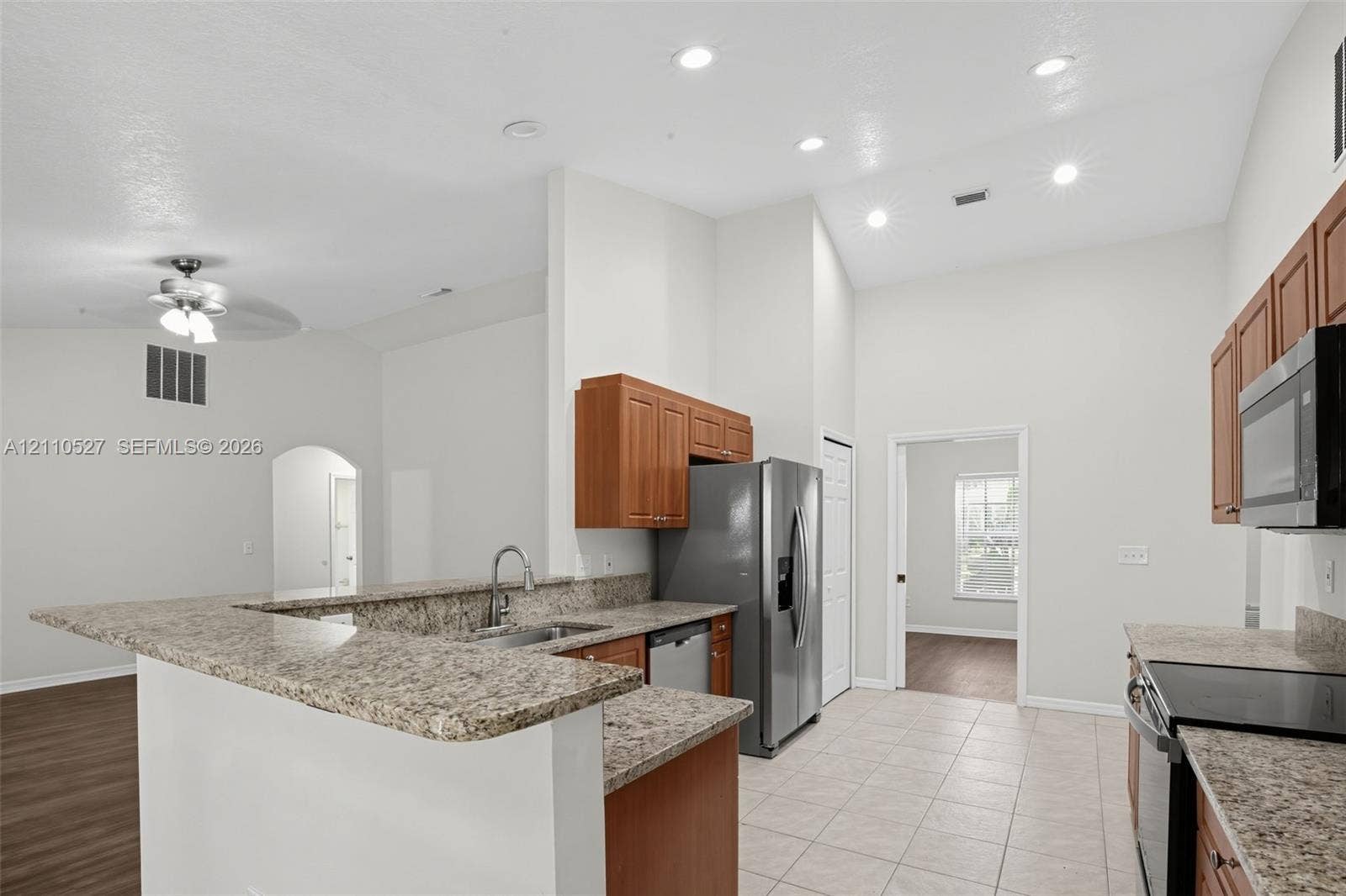 5509 NW Commodore Terrace, Port St Lucie, FL 34983 Kitchen featuring stone-finish countertops, stainless steel appliances, wood cabinetry, recessed lighting, and tile flooring