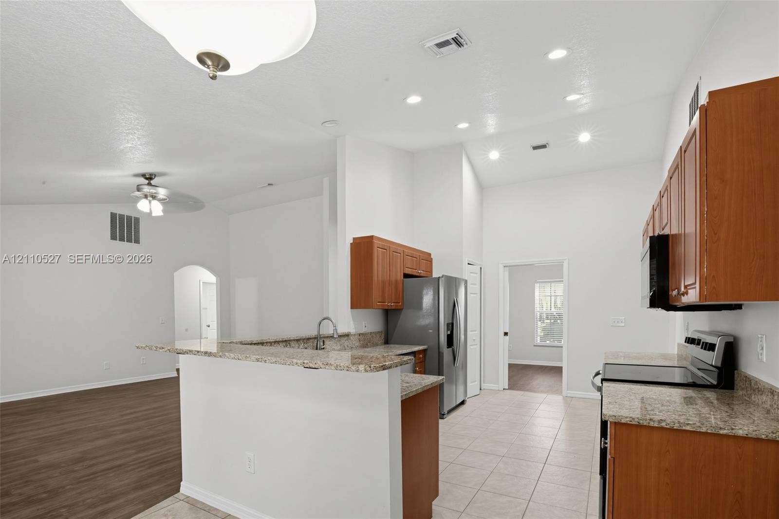 5509 NW Commodore Terrace, Port St Lucie, FL 34983 Kitchen featuring wood cabinetry, stone-finish countertops, stainless steel appliances, recessed ceiling lighting, and tiled flooring