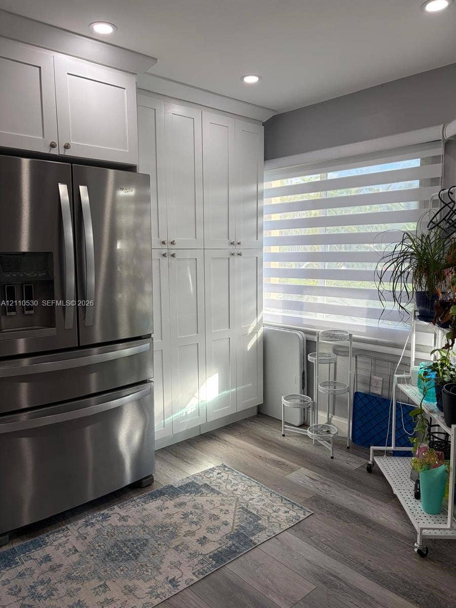 13255 SW 16th Court, #K112, Pembroke Pines, FL 33027 Shaker-style white cabinetry, floor-to-ceiling built-in pantry storage, stainless steel refrigerator, and wood-finish flooring