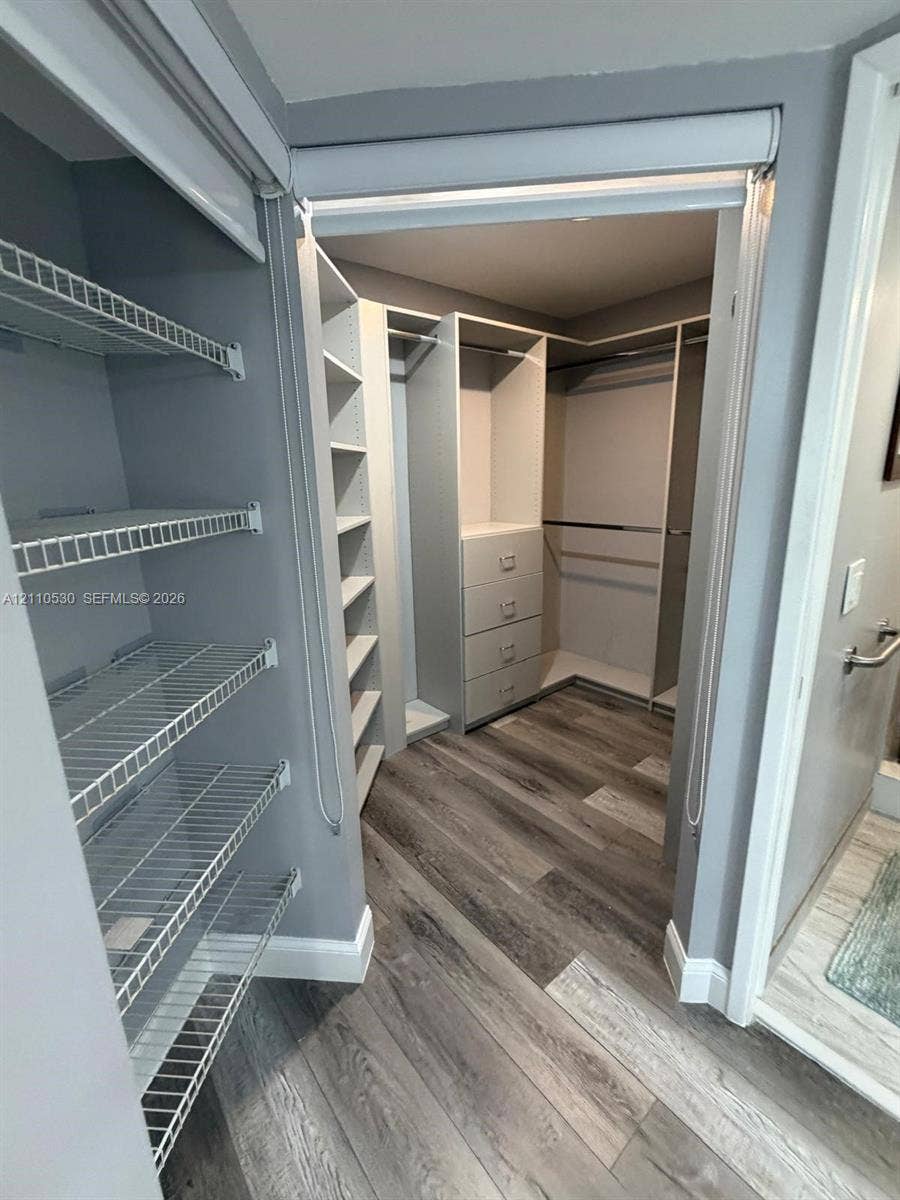 13255 SW 16th Court, #K112, Pembroke Pines, FL 33027 Walk-in closet featuring wood-finish flooring, built-in shelving, integrated dresser drawers, and metal wire rack storage