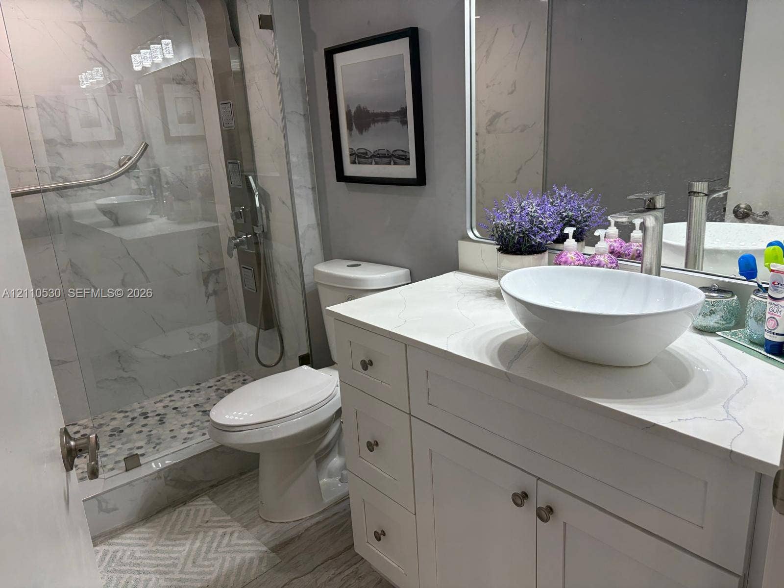 13255 SW 16th Court, #K112, Pembroke Pines, FL 33027 Bathroom featuring a vanity with a white vessel sink, quartz countertop, walk-in shower with stone-tile flooring, floor-to-ceiling tile surround, and polished hardware