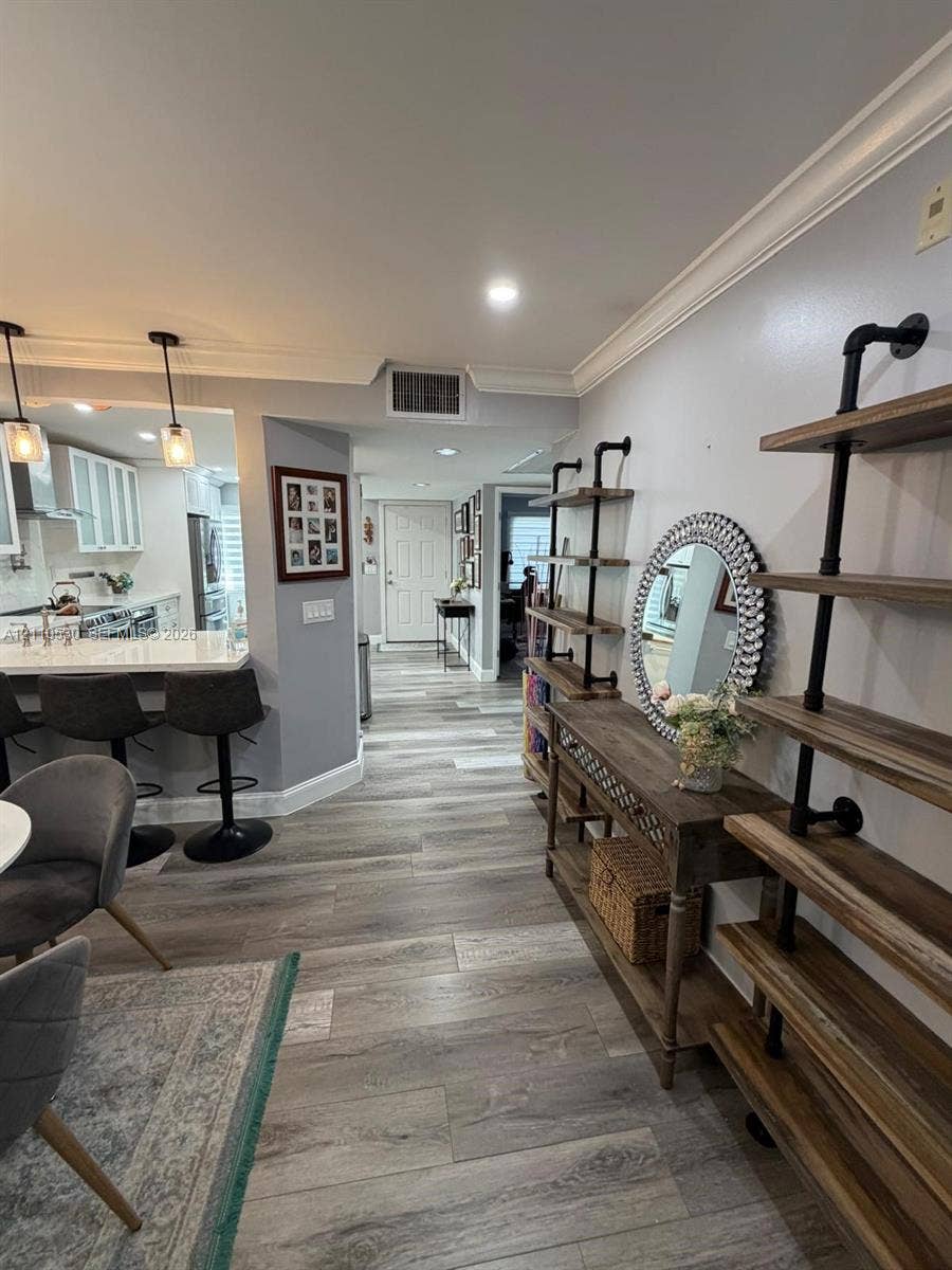 13255 SW 16th Court, #K112, Pembroke Pines, FL 33027 Wood-finish flooring, crown molding, recessed lighting, and kitchen peninsula featuring quartz countertops and pendant lighting