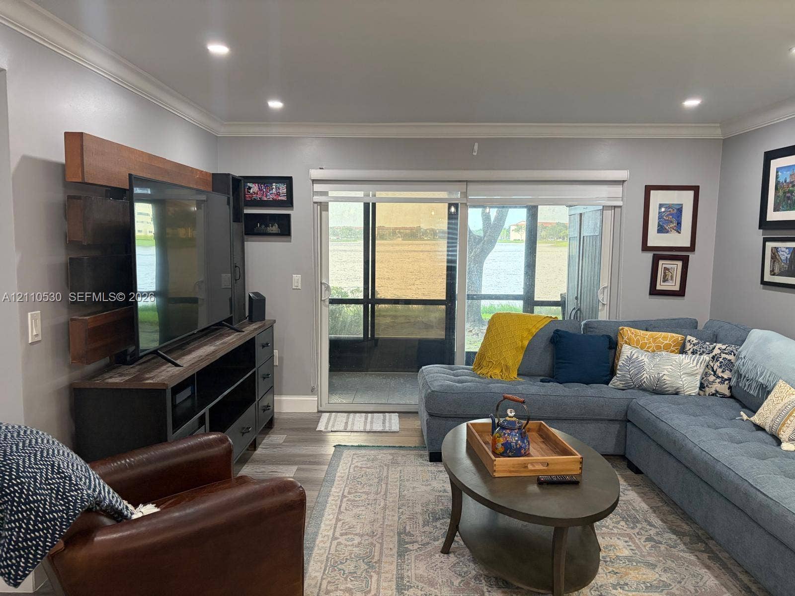 13255 SW 16th Court, #K112, Pembroke Pines, FL 33027 Living area featuring wood-finish flooring, recessed lighting, crown molding, and large sliding glass doors opening to a screened enclosure