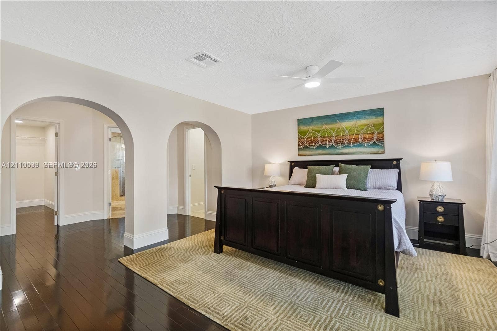 Interior space featuring dark wood-finish flooring, dual arched entryways, and a ceiling-mounted light fixture with an integrated fan