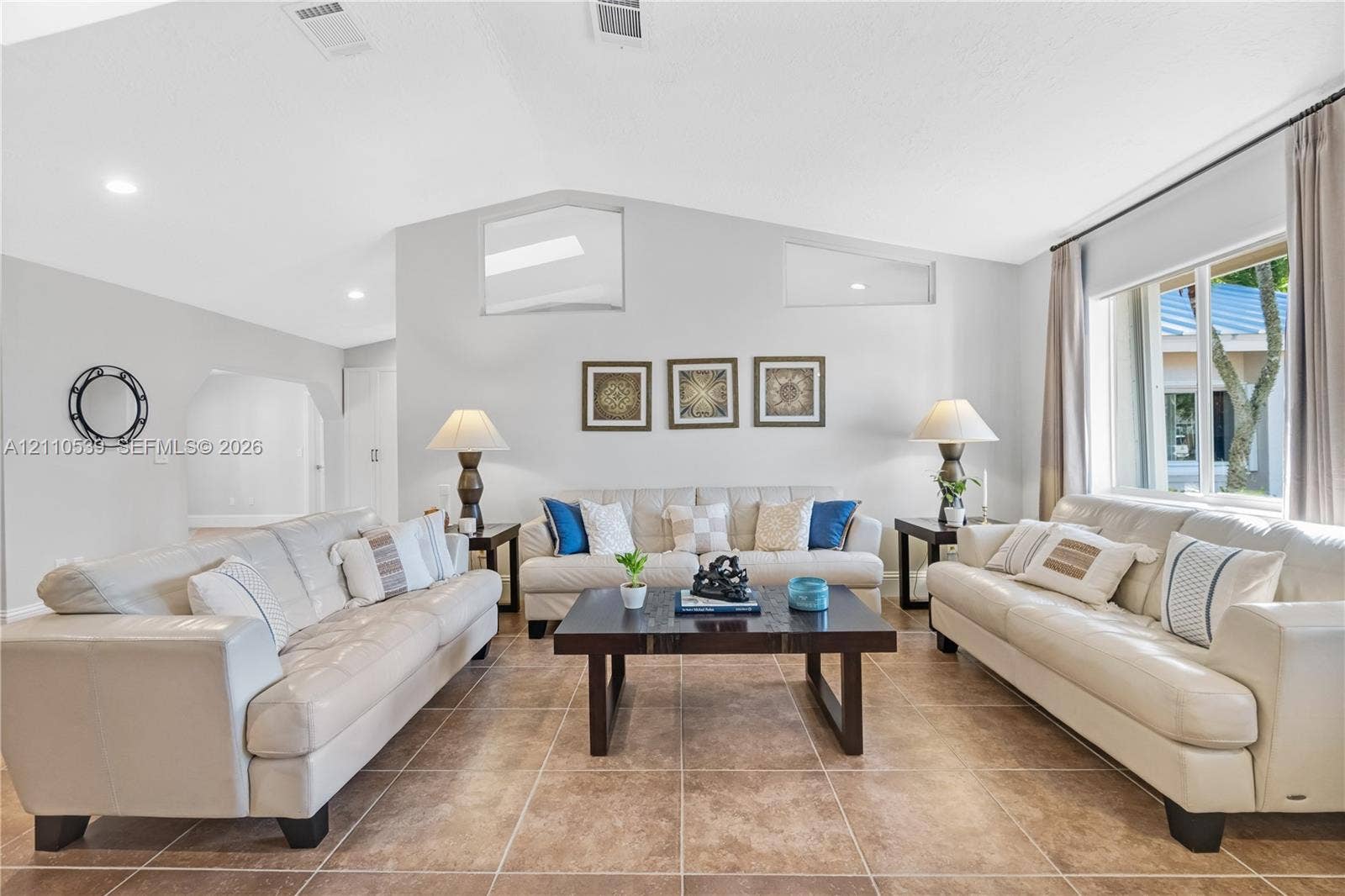 Living room featuring vaulted ceilings, oversized tile flooring, recessed lighting, and clerestory windows