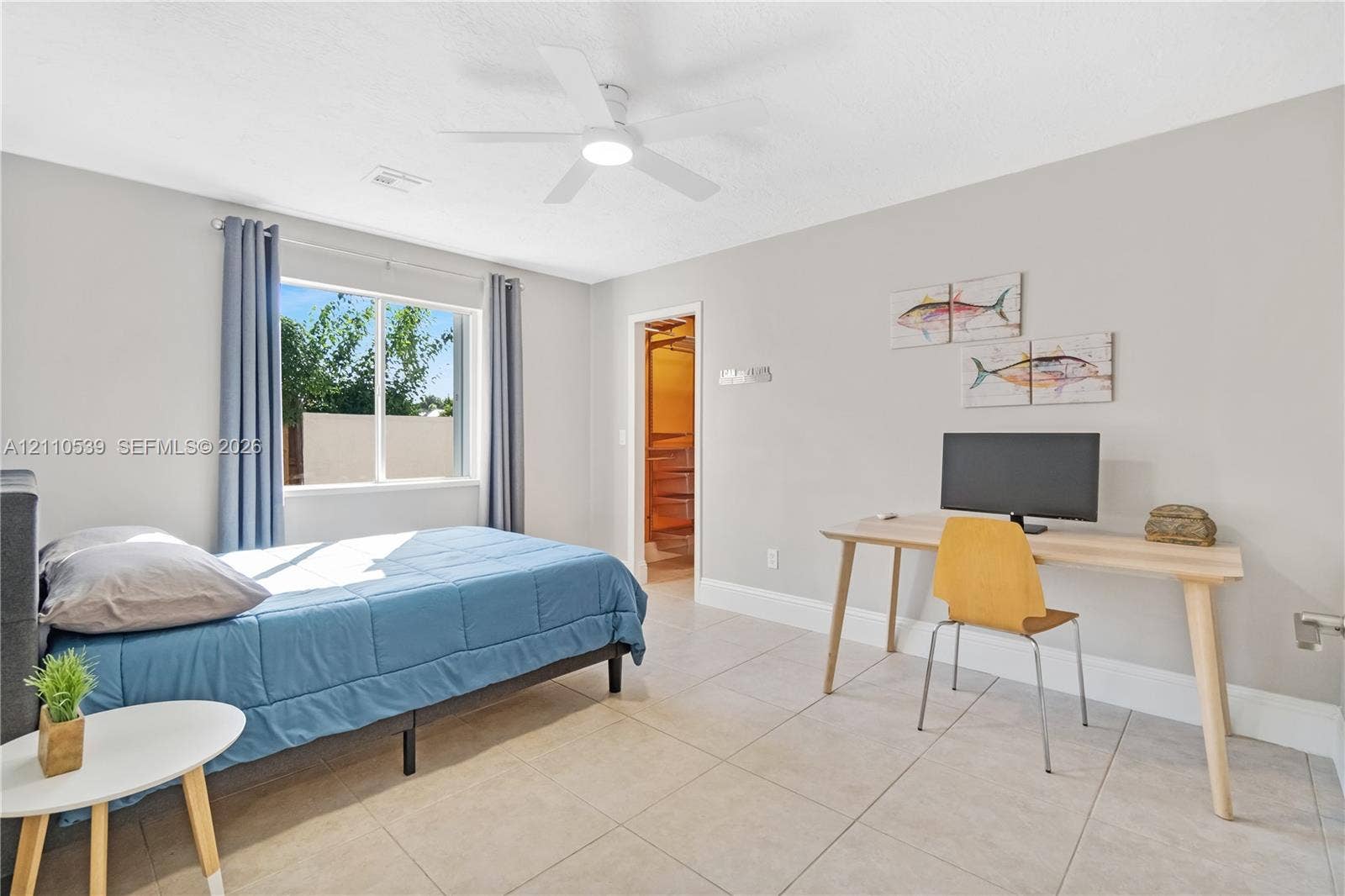 Neutral-toned interior featuring large-format tile flooring, a multi-blade ceiling fan with integrated lighting, and a single-pane window