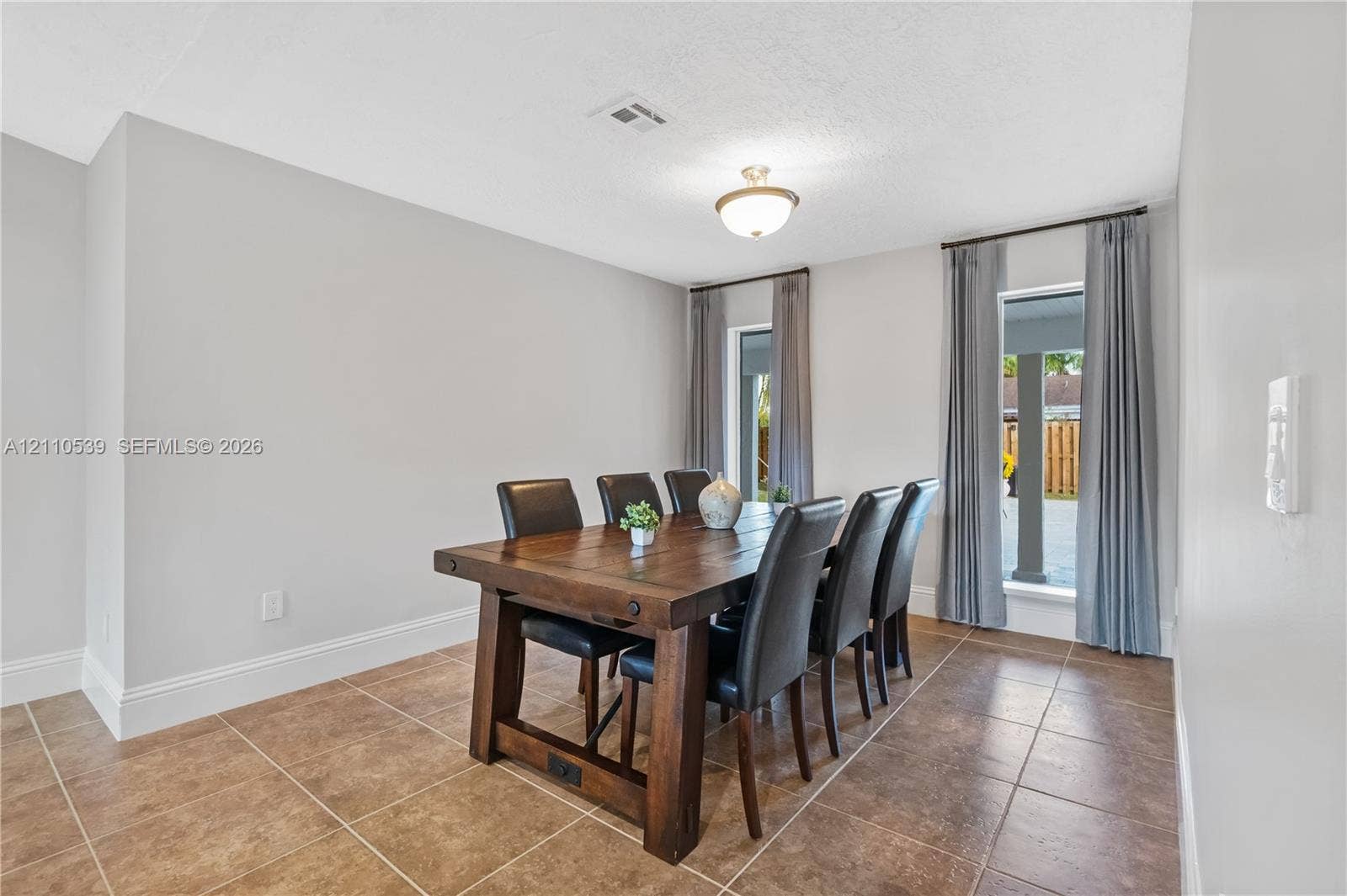 Neutral wall finishes, ceramic tile flooring, dual floor-to-ceiling windows, and a flush-mount ceiling light fixture