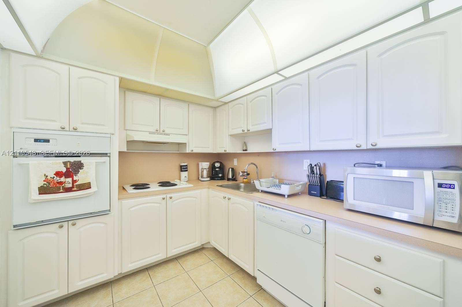 Kitchen featuring white cabinetry, integrated wall oven, white cooktop, tiled flooring, and recessed architectural lighting