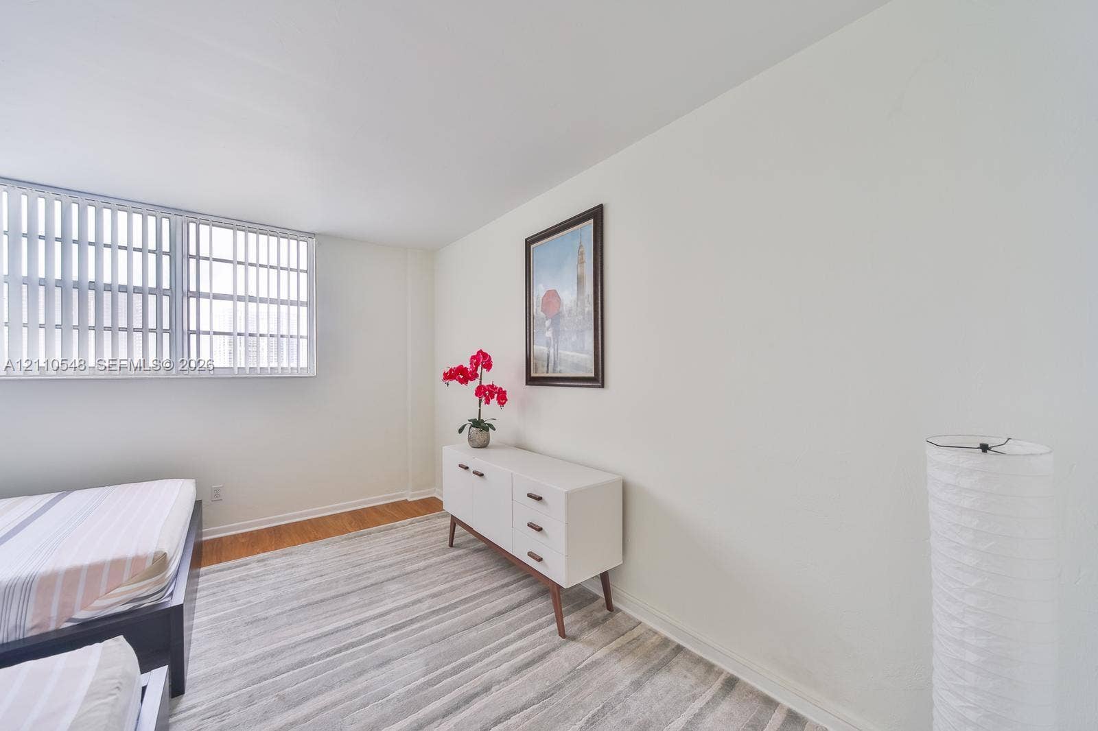Interior space featuring neutral wall paint, wood-finish flooring, and horizontal window blinds