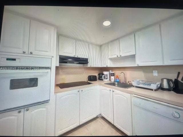 Kitchen featuring white shaker-style cabinetry, solid-surface countertops, built-in wall oven, flat cooktop, and undermount stainless steel sink