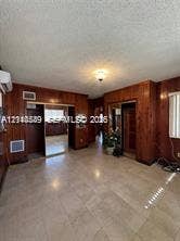 500 SW 39th Court, Miami, FL 33134 Wood-panelled interior walls, neutral tile flooring, mirrored closet doors, and a ceiling-mounted light fixture