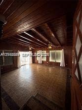 500 SW 39th Court, Miami, FL 33134 Interior space featuring natural wood-paneled walls, exposed wood-beam ceiling, grid-patterned tile flooring, and multiple windows