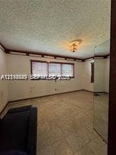 500 SW 39th Court, Miami, FL 33134 Room featuring wood crown molding, a semi-flush mount ceiling light fixture, a triple-pane window, and mirrored closet doors