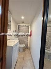 500 SW 39th Court, Miami, FL 33134 White vanity with a rectangular sink, neutral tile flooring, recessed ceiling lighting, and a bathtub with a shower enclosure