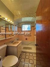 500 SW 39th Court, Miami, FL 33134 Bathroom featuring a vanity with an integrated basin, wall-mounted mirror cabinetry, and decorative tiled tub surround with an overhead shower fixture