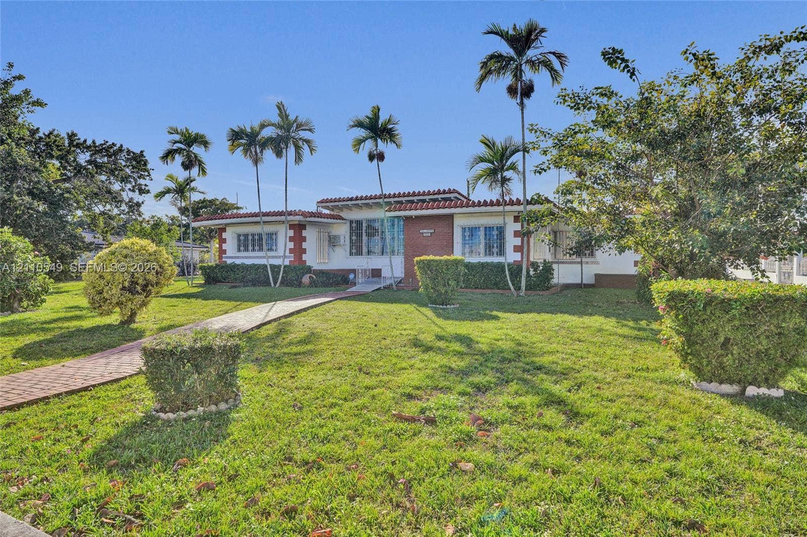 500 SW 39th Court, Miami, FL 33134 Single-story exterior featuring a brick facade with clay tile roof accents, accompanied by a paver walkway and established landscaping with mature palms