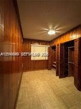 500 SW 39th Court, Miami, FL 33134 Room featuring vertical wood-paneled walls, tile flooring, recessed ceiling lighting, and built-in closet storage with louvered doors
