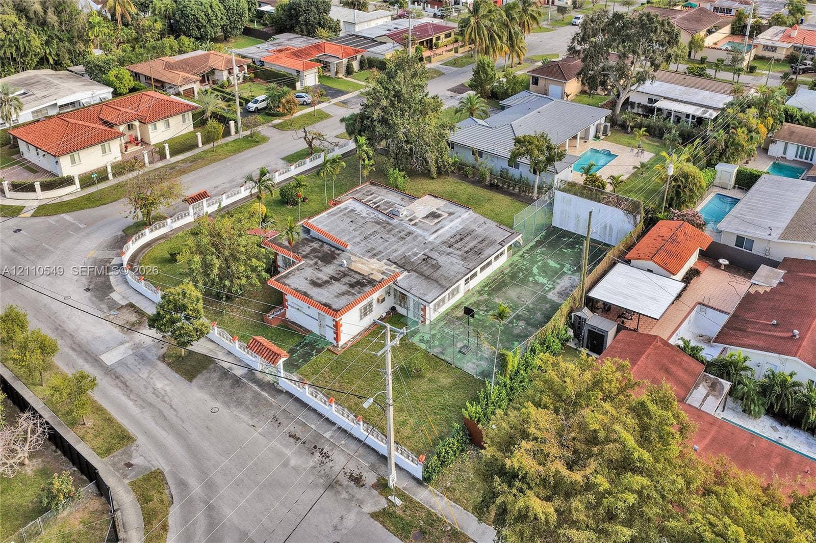 500 SW 39th Court, Miami, FL 33134 Aerial perspective featuring a corner lot property with a private fenced tennis court and a perimeter masonry wall