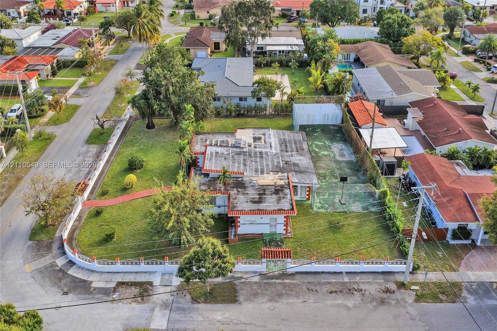 500 SW 39th Court, Miami, FL 33134 Corner lot featuring a perimeter wall with decorative accents, an expansive yard, and a dedicated hard-surface sports court