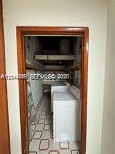 500 SW 39th Court, Miami, FL 33134 Utility space featuring built-in wooden shelving, patterned flooring, and a door frame with wood trim