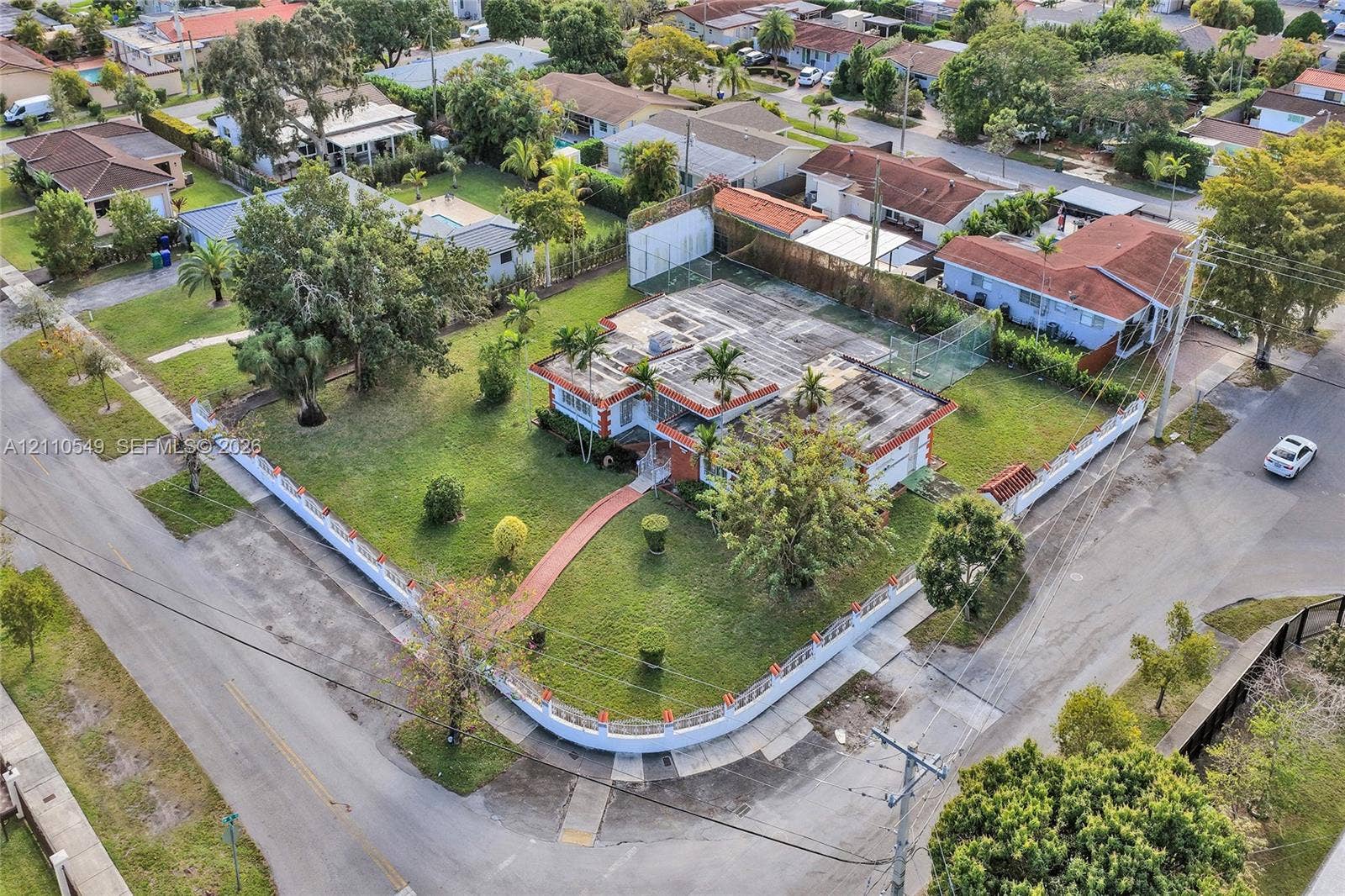 500 SW 39th Court, Miami, FL 33134 Corner lot property featuring a wraparound masonry perimeter wall, expansive manicured lawn, established landscaping, and paved walkway