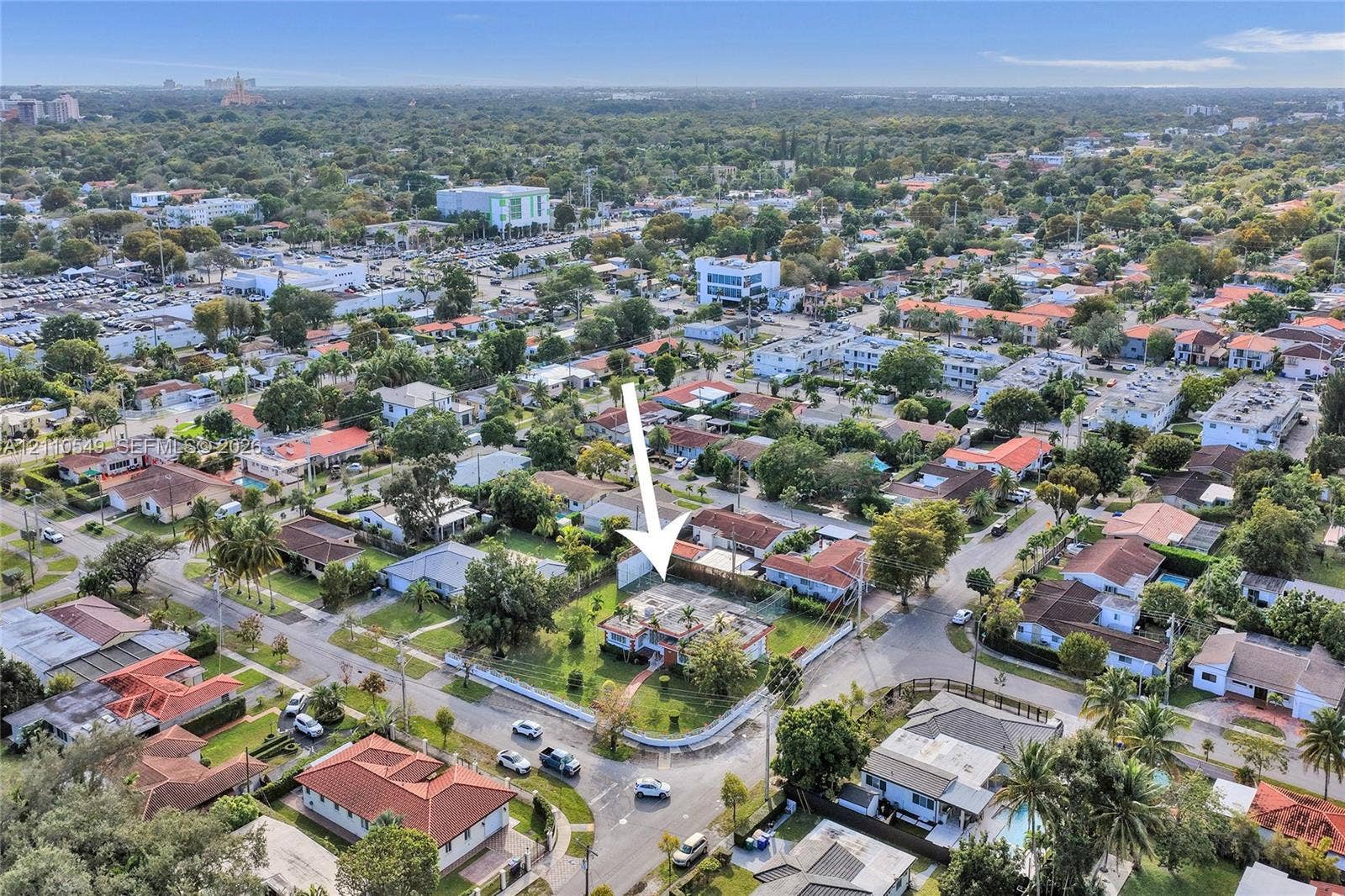 500 SW 39th Court, Miami, FL 33134 Corner-lot property featuring a multi-pitched roof, paved driveway, mature perimeter landscaping, and a central lawn area