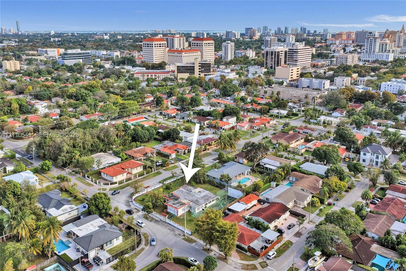 500 SW 39th Court, Miami, FL 33134 Aerial perspective of a single-story residence situated on a corner lot featuring perimeter fencing, mature trees, and a concrete driveway