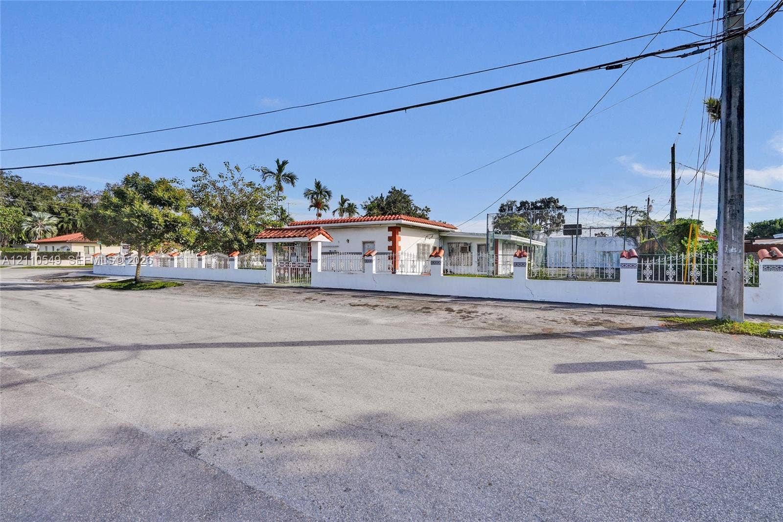 500 SW 39th Court, Miami, FL 33134 Single-story exterior featuring a clay tile roof, stucco facade, decorative corner brickwork, and a perimeter masonry wall with integrated fencing