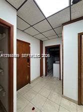 500 SW 39th Court, Miami, FL 33134 Interior space featuring neutral tile flooring, wood-finish doors with matching door frames, and a drop ceiling with integrated lighting panels