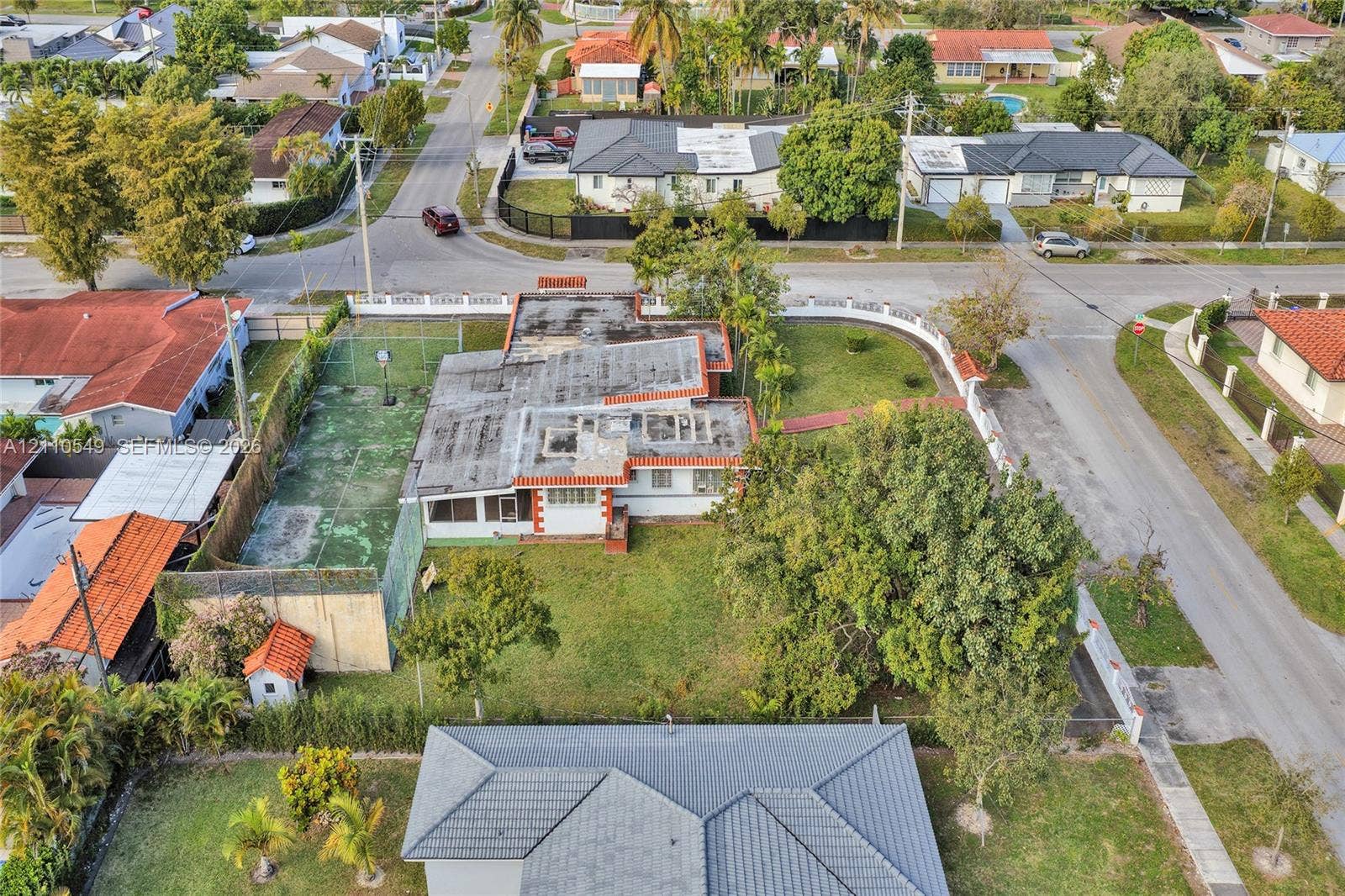 500 SW 39th Court, Miami, FL 33134 Corner lot property featuring an enclosed multi-use sports court, expansive green space, mature trees, and perimeter fencing