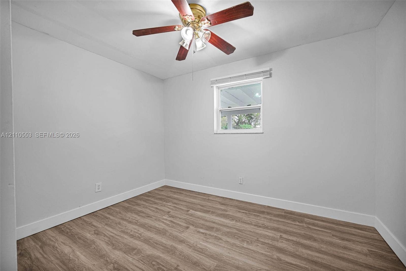 16611 SW 108th Court, Miami, FL 33157 Interior room featuring wood-finish flooring, neutral wall tones, a ceiling fan with multi-light fixture, and a single window with blinds