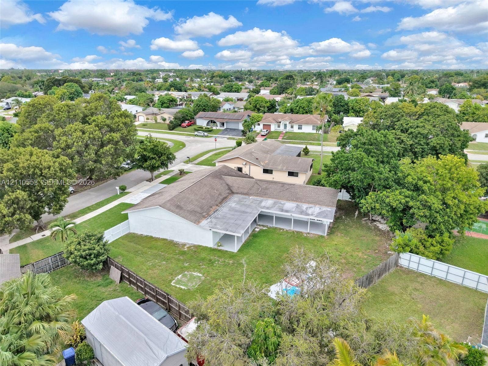 16611 SW 108th Court, Miami, FL 33157 Single-story residence featuring a shingle roof, rear-facing covered patio, fenced backyard, and a detached storage structure