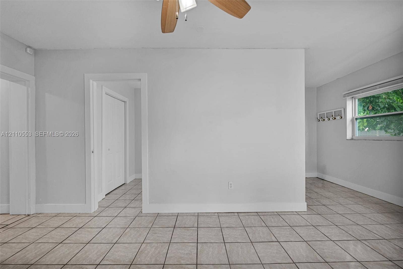 16611 SW 108th Court, Miami, FL 33157 Neutral-toned interior space featuring large-format tile flooring, a ceiling fan with light fixture, and a wall-mounted hook rack