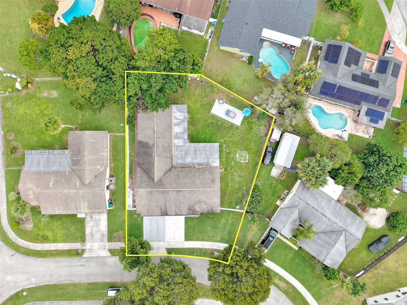 16611 SW 108th Court, Miami, FL 33157 Aerial perspective of the property featuring a structured lot with an L-shaped roofline, mature trees, and a paved driveway