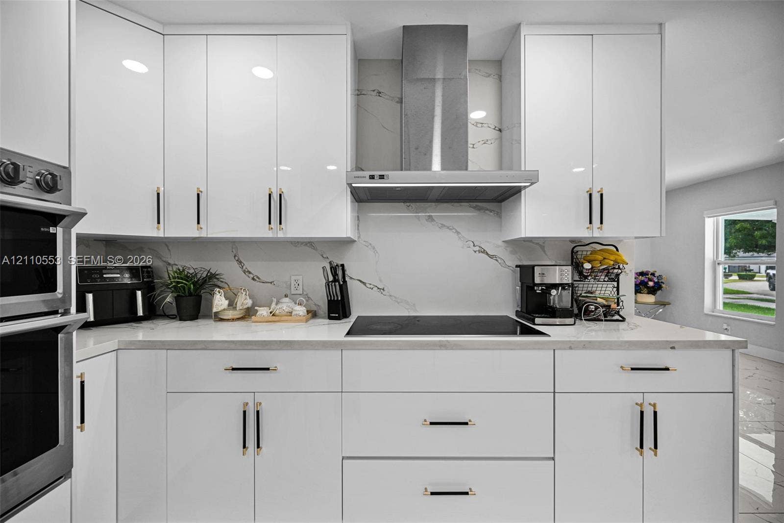 16611 SW 108th Court, Miami, FL 33157 Kitchen featuring glossy white flat-panel cabinetry, white stone-patterned backsplash, stainless steel chimney-style range hood, electric cooktop, and built-in double wall oven