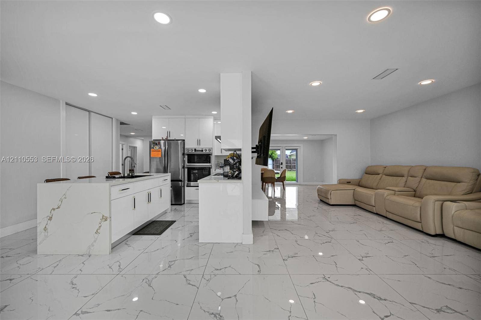 16611 SW 108th Court, Miami, FL 33157 Kitchen area featuring an island with a waterfall countertop, white flat-panel cabinetry, recessed lighting, and large-format tile flooring