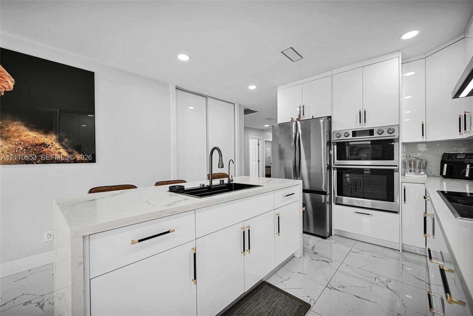 16611 SW 108th Court, Miami, FL 33157 Kitchen featuring high-gloss white cabinetry, white stone-finish waterfall edge island, stainless steel double wall oven, integrated refrigerator, and large-format tile flooring