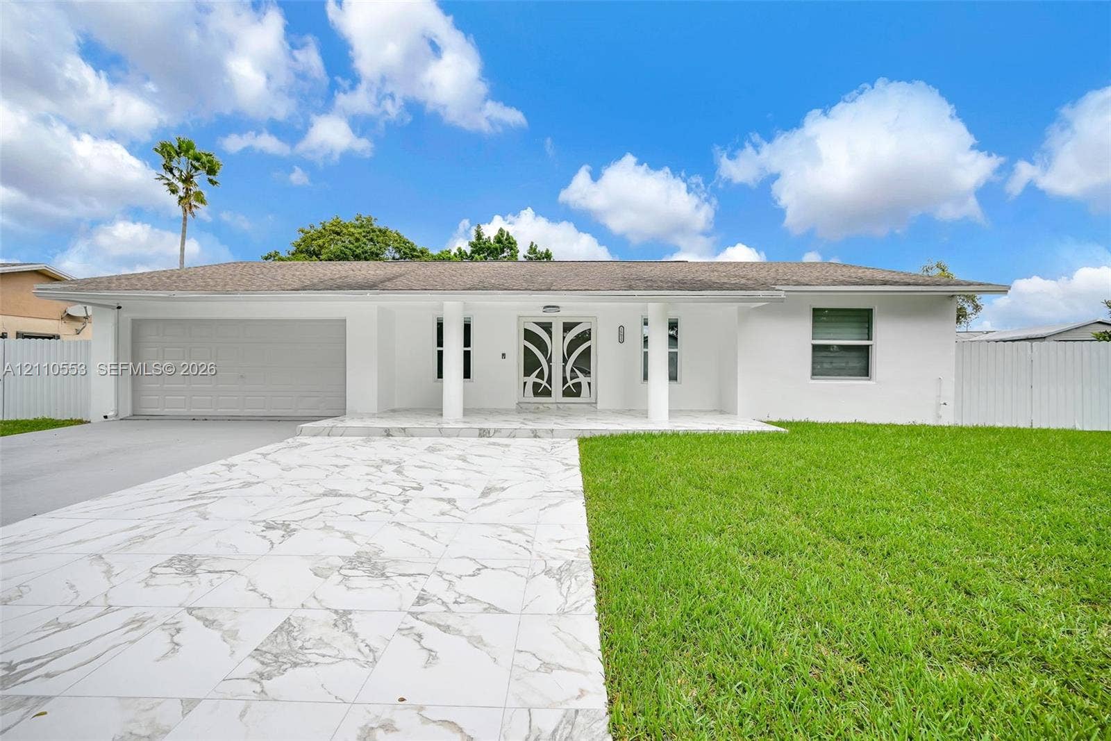 16611 SW 108th Court, Miami, FL 33157 Single-story exterior featuring a stone-finish driveway, decorative glass double front doors, covered porch with structural columns, and solid fencing