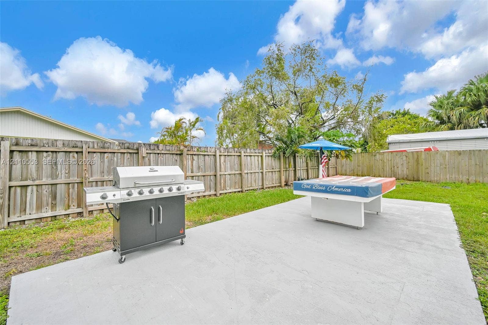 16611 SW 108th Court, Miami, FL 33157 Spacious backyard featuring a large concrete patio, privacy wood fencing, and mature landscaping