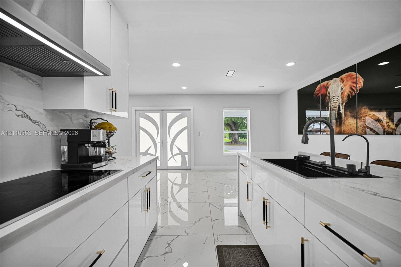 16611 SW 108th Court, Miami, FL 33157 Kitchen featuring high-gloss cabinetry, stone-surface countertops, large-format tile flooring, a center island with an integrated sink, and matte hardware accents