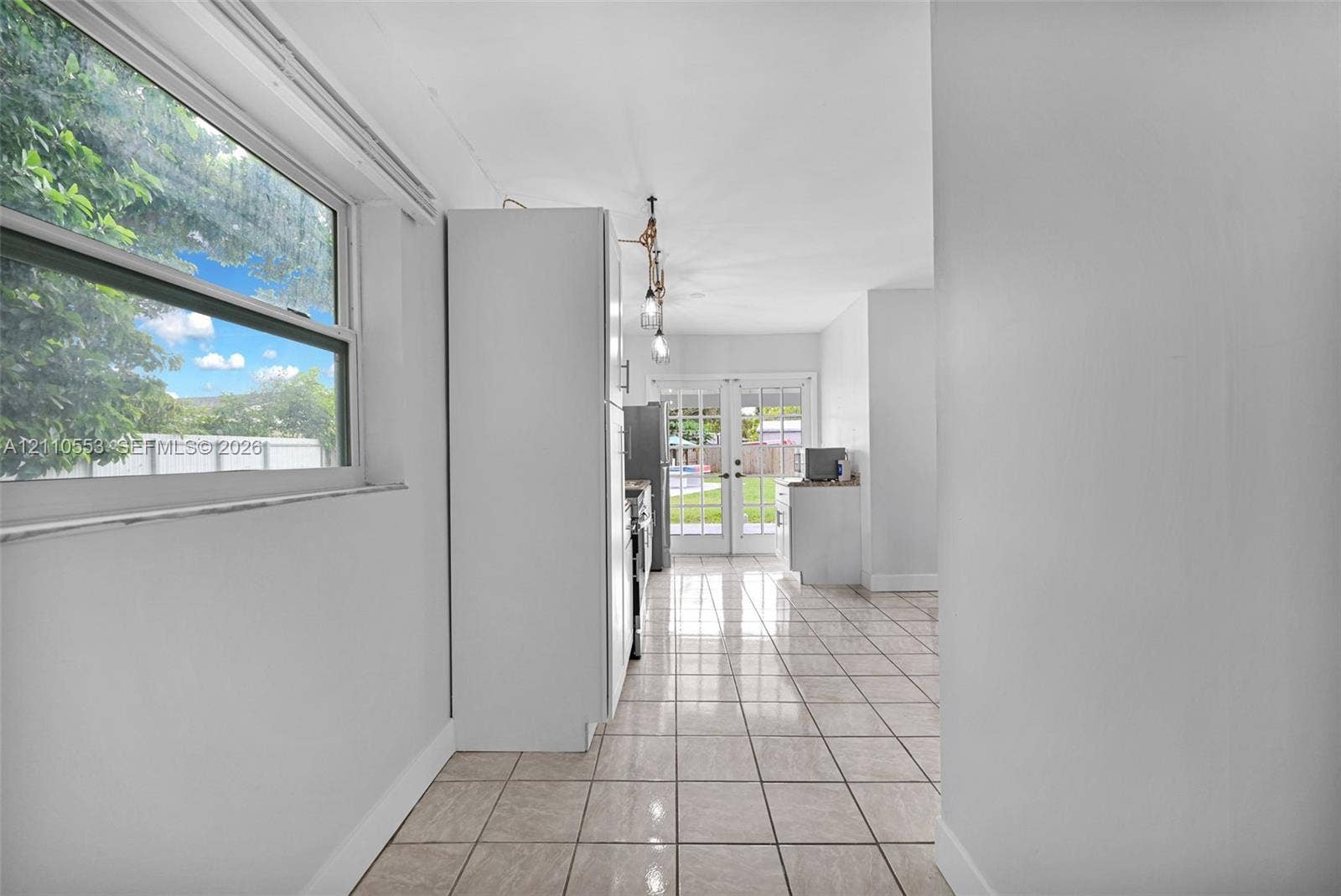 16611 SW 108th Court, Miami, FL 33157 Neutral tile flooring, large single-hung window, white cabinetry, and multi-pane glass french doors