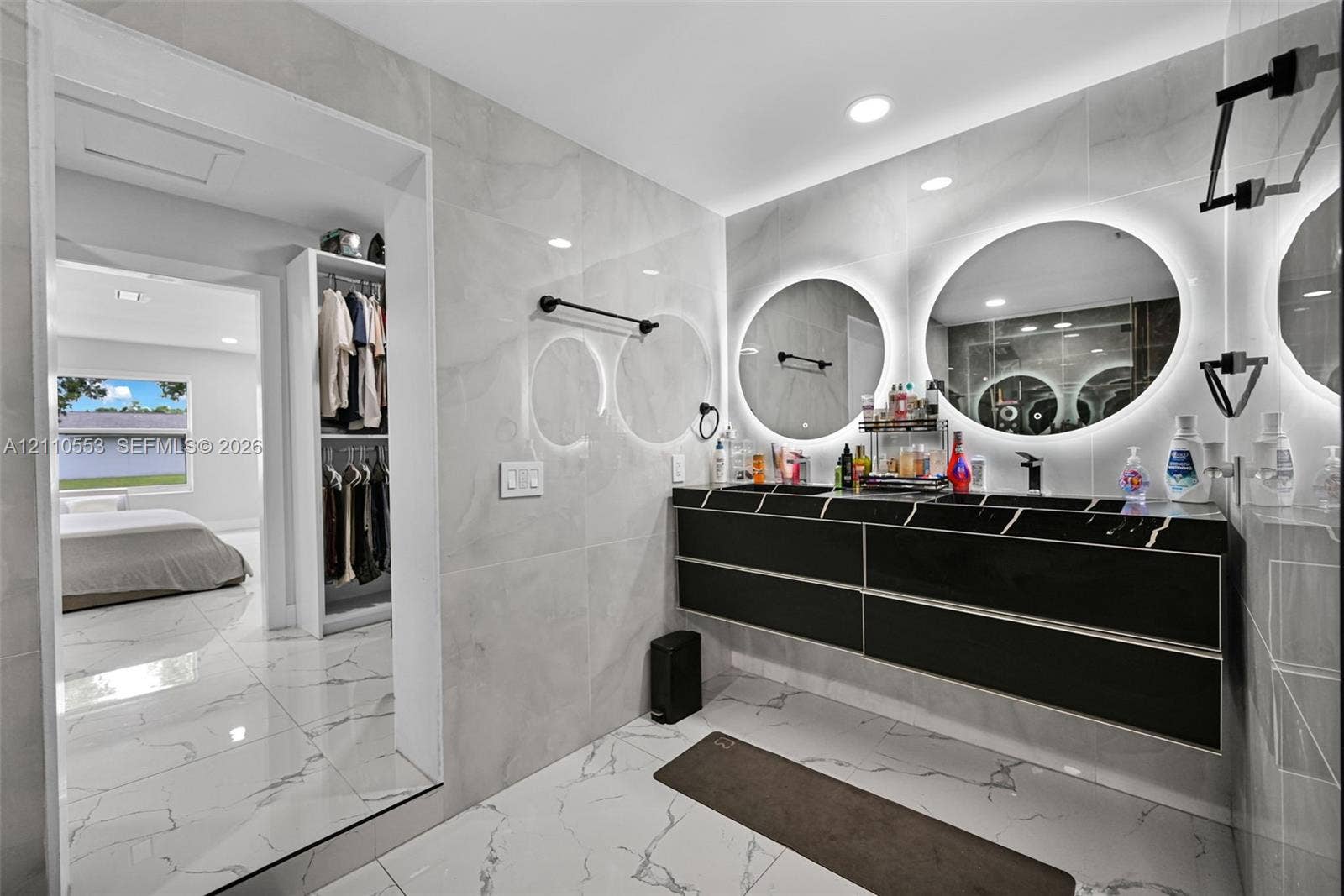 16611 SW 108th Court, Miami, FL 33157 Floating black vanity featuring dual vessel sinks, quartz countertop, large circular backlit mirrors, and floor-to-ceiling large-format wall and floor tile