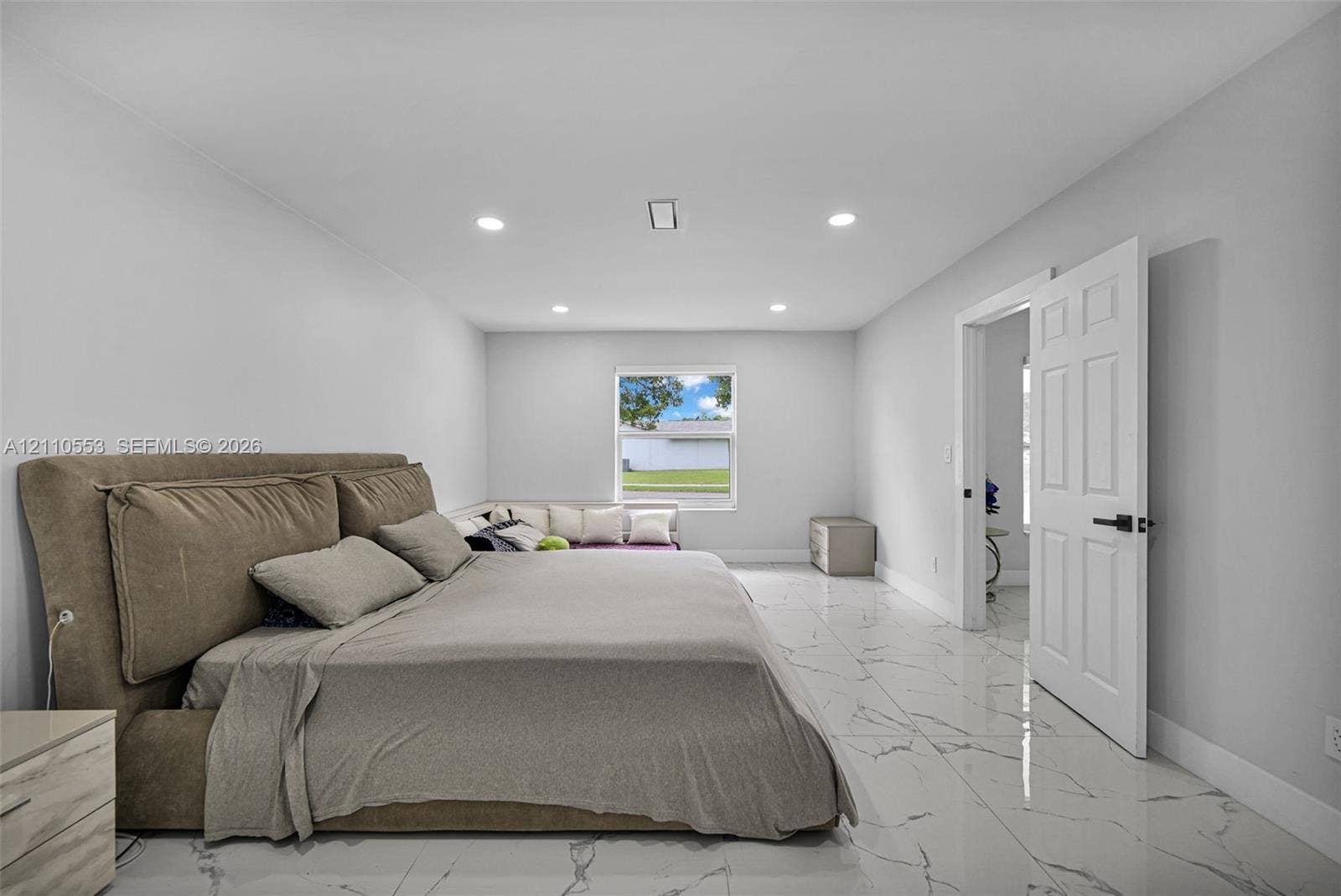 16611 SW 108th Court, Miami, FL 33157 Interior room featuring large-format tile flooring with veining, recessed lighting, and a multi-panel door with matte black hardware