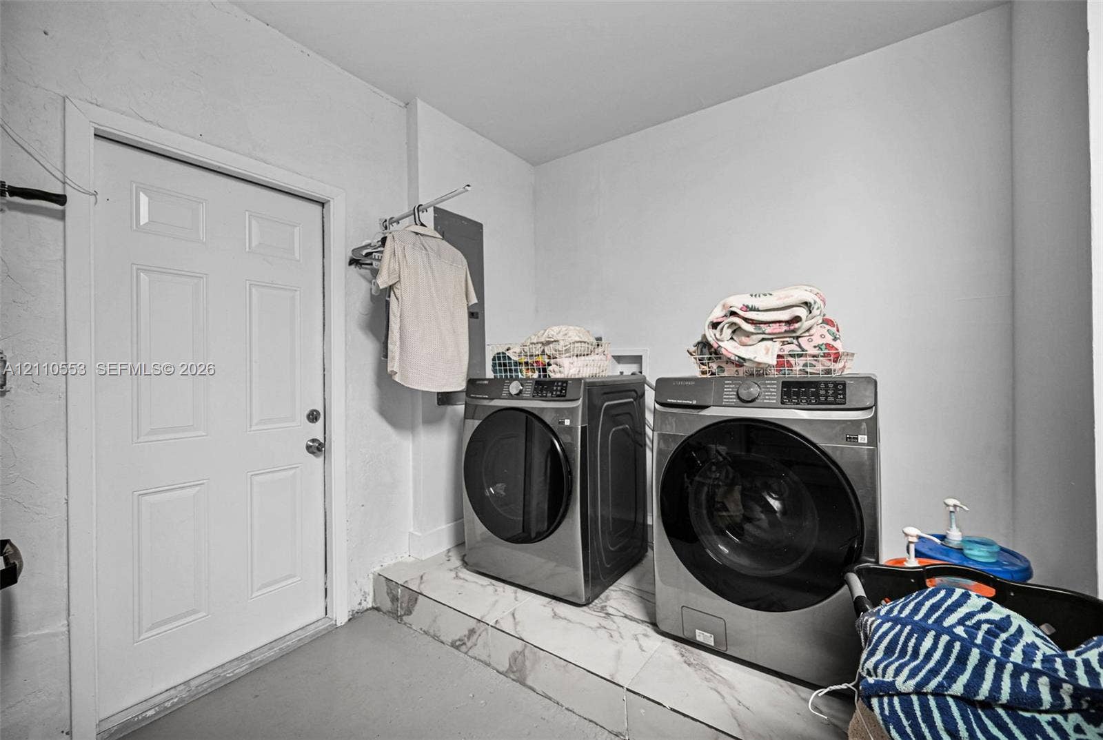 16611 SW 108th Court, Miami, FL 33157 Laundry area featuring elevated tile flooring, white six-panel door, and integrated wall-mounted clothing rack