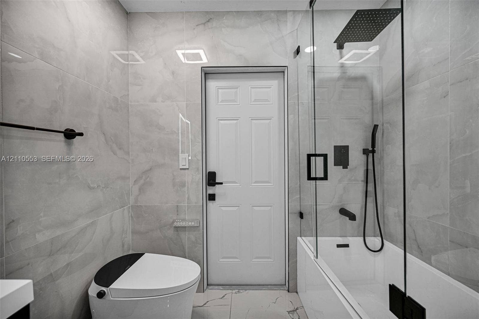 16611 SW 108th Court, Miami, FL 33157 Full-height large-format wall tiling, glass-enclosed shower with a rainfall showerhead, matte black hardware, and integrated digital-flush toilet