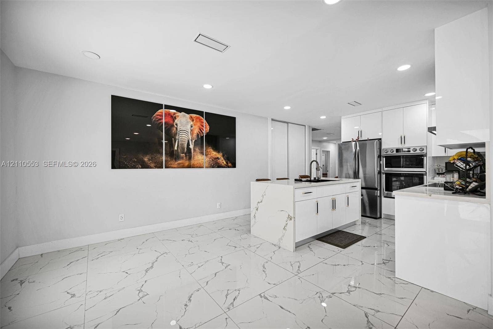 16611 SW 108th Court, Miami, FL 33157 Kitchen featuring white high-gloss cabinetry, center island with stone-finish waterfall countertop, stainless steel double wall oven, and large-format porcelain tile flooring