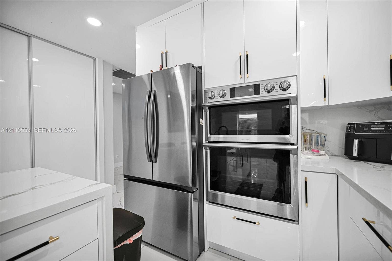 16611 SW 108th Court, Miami, FL 33157 Kitchen featuring high-gloss white cabinetry, stone-finish countertops, stainless steel appliances, a double wall oven, and metallic hardware
