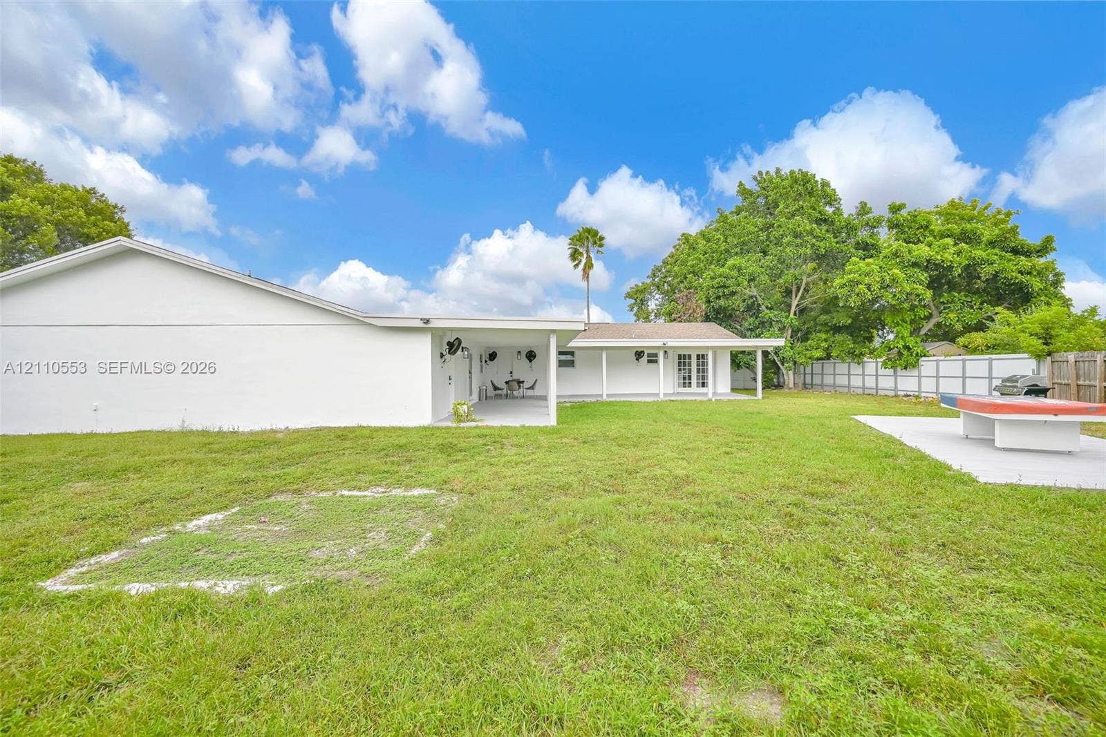 16611 SW 108th Court, Miami, FL 33157 Backyard featuring a sprawling lawn, a covered patio area, concrete hardscaping, and perimeter wood and metal fencing
