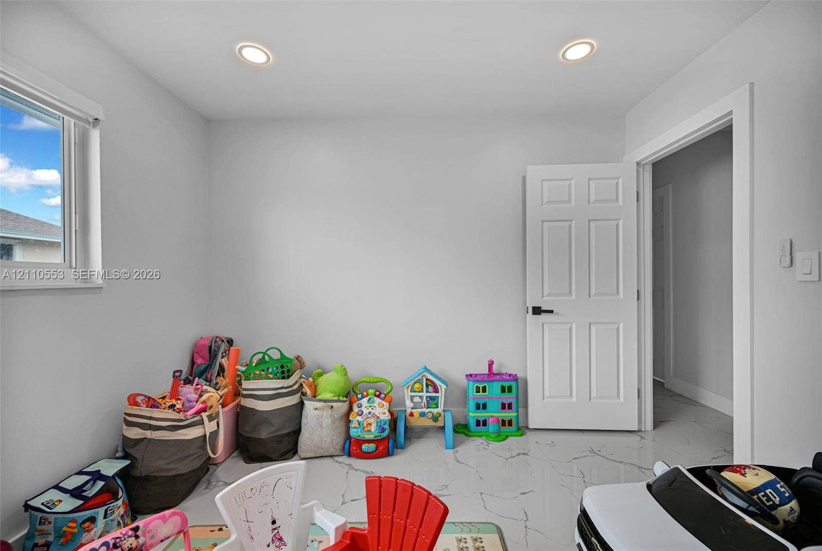 16611 SW 108th Court, Miami, FL 33157 Interior room featuring white tile flooring with grey veining, neutral wall paint, recessed lighting, and a white interior door with matte black hardware