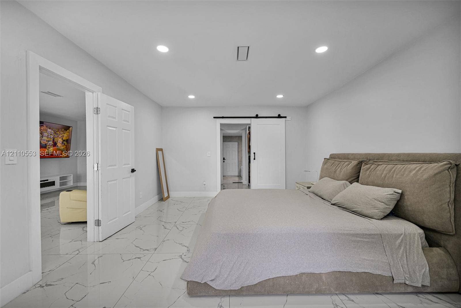 16611 SW 108th Court, Miami, FL 33157 Polished tile flooring with veining, recessed lighting, white panel doors, and a sliding barn door with matte black hardware